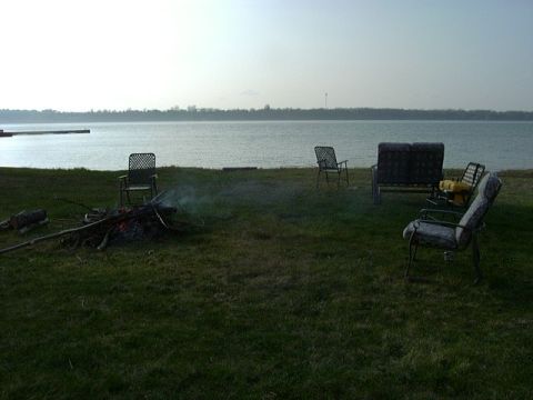 1992 Ford Bronco - A lakeside scene features chairs arranged around a campfire, with the calm water stretching to the horizon.