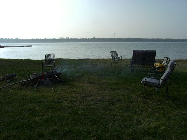 Lakeside scene with chairs and a campfire