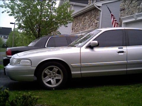 2002 Ford Crown Victoria - A silver 2002 Ford Crown Victoria is parked next to a black car.