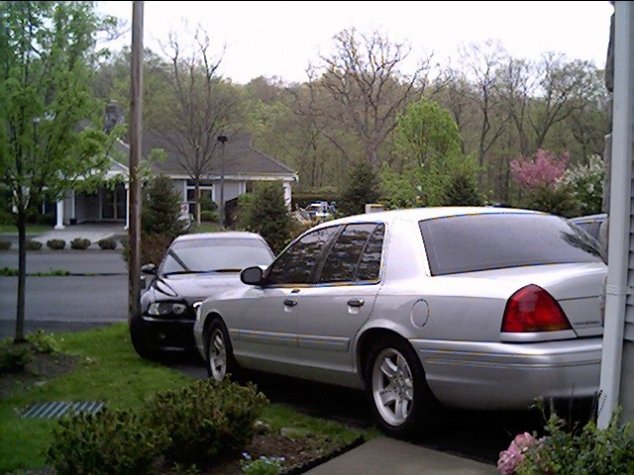 Silver Ford Crown Victoria parked in driveway, three-quarter rear view