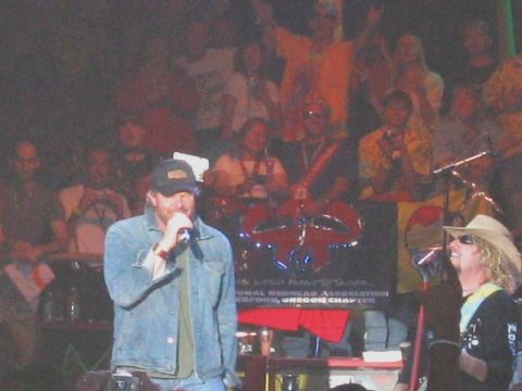 1989 Ford Bronco - Concert stage shot of a bearded singer in a denim jacket and ball cap holding a microphone, with a guitarist in a straw cowboy hat and sung…