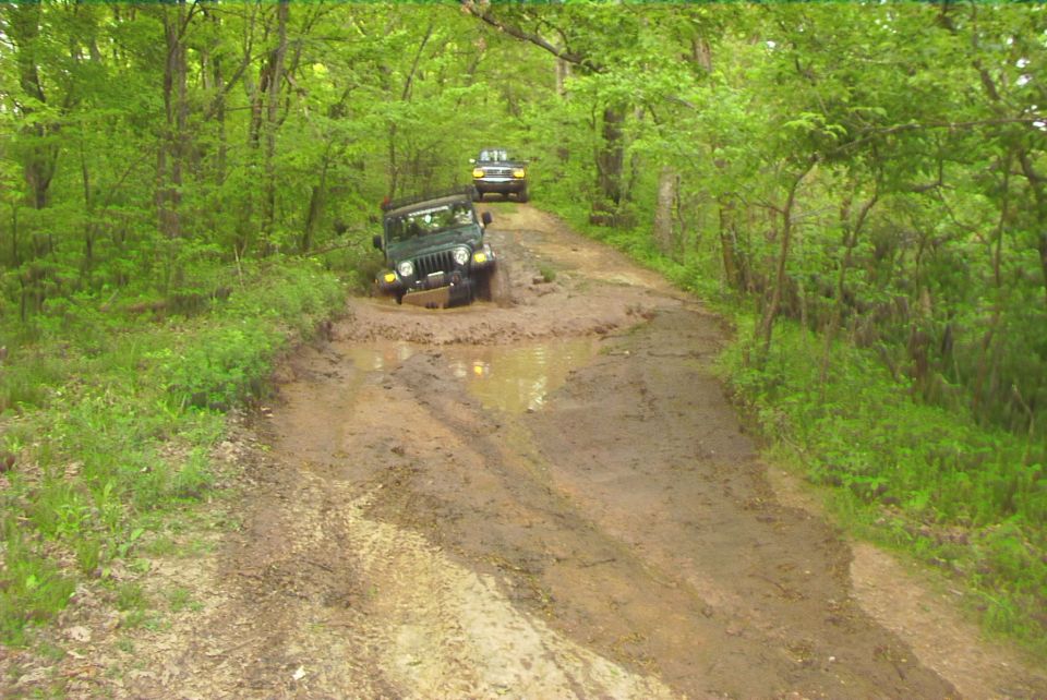 Jeep Wrangler stuck in mud on a dirt road, another SUV behind it