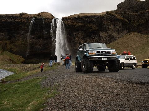 1996 Ford Bronco - A lifted 1996 Ford Bronco is parked in front of a waterfall, with other vehicles and people nearby.