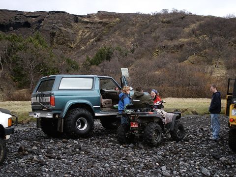 1996 Ford Bronco - A teal SUV and an ATV are parked on a rocky terrain with people gathered around.