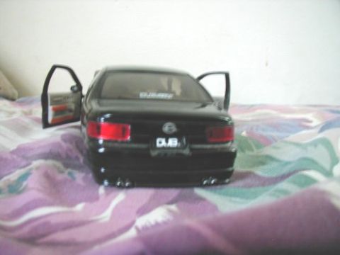 1997 Ford Taurus - A black toy car, possibly a model, is shown with its doors open, displaying interior details and DUB badging on the rear.