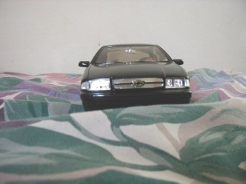 1997 Ford Taurus - A black sedan model is shown from the front, resting on a colorful, patterned fabric.