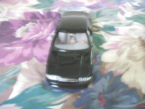 1997 Ford Taurus - A black toy car is positioned on a fabric with a floral pattern.