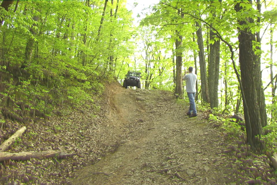 Jeep Wrangler climbing a dirt trail in a forest
