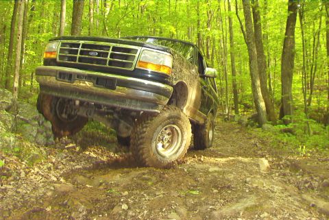 1995 Ford Bronco - This 1995 Ford Bronco tackles a challenging off-road course, demonstrating its capability on rough terrain.