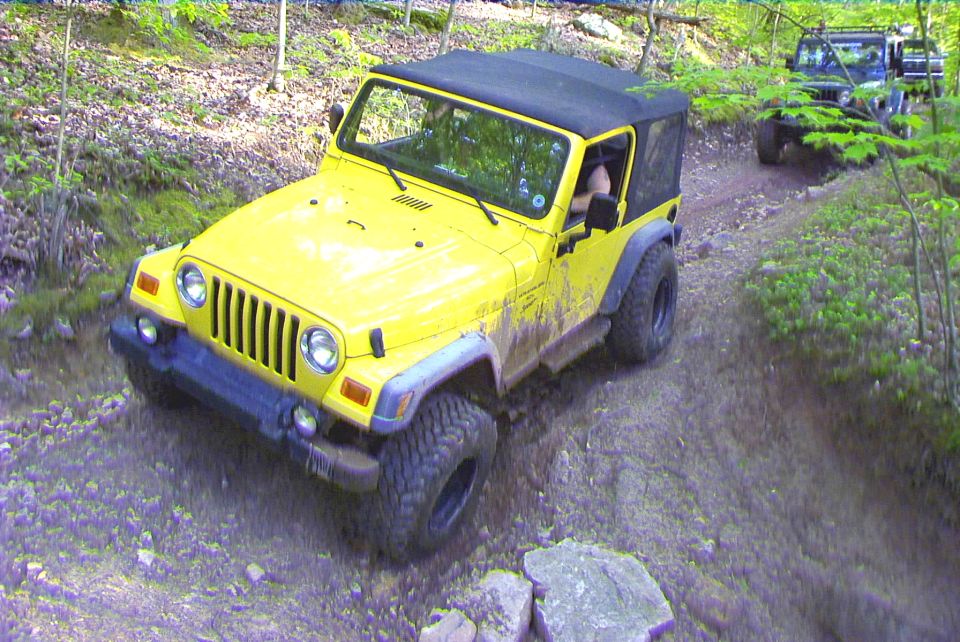 Yellow Jeep Wrangler TJ driving on a dirt trail with another Jeep behind it