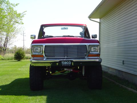1978 Ford Bronco - Head-on front view of a red 1978-79 Ford Bronco with a chrome grille and bumper, rectangular headlights, and a "Torco Racing Fuels" plate.…