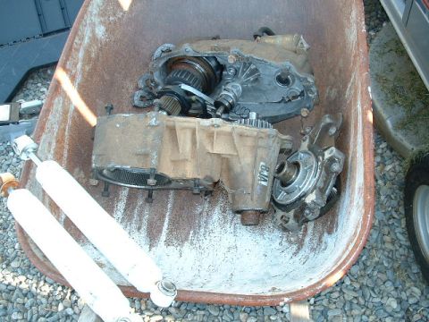 1991 Ford Bronco - A transfer case and two shock absorbers are pictured in a wheelbarrow, suggesting they are parts for a vehicle.