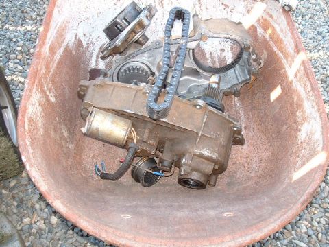 1991 Ford Bronco - A rusty transfer case with its drive chain and electric motor is shown in a wheelbarrow.