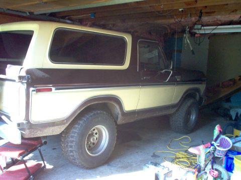 1979 Ford Bronco - The rear three-quarter view of a two-tone Ford Bronco is captured inside a cluttered garage.