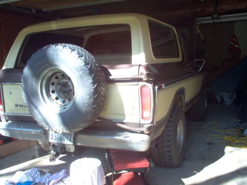 1979 Ford Bronco - The rear of a two-tone brown and tan 1978 Ford Bronco is visible, parked indoors with a spare tire mounted on the back.