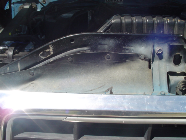 Close-up of a vehicle's engine bay, showing the radiator support and surrounding components. A sticker that says 'LOCKER' is visible