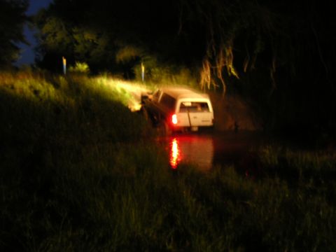 1984 Chevrolet Blazer - Pickup truck with camper shell navigates through water at night.