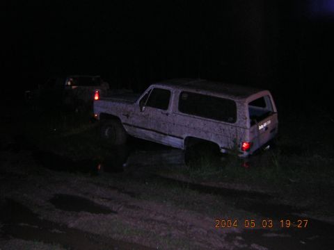1984 Chevrolet Blazer - A mud-caked 1984 Chevrolet Blazer is parked on rough terrain at night, with another vehicle visible in the background.