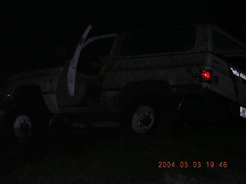 Muddy white square-body 4x4 SUV at night with driver door open and Delta 4X4 decal