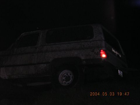 1984 Chevrolet Blazer - A dark, rear view of an SUV is visible with a lit taillight and text on its side.