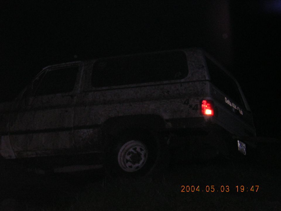 SUV rear view, dark, with visible taillight and text on side