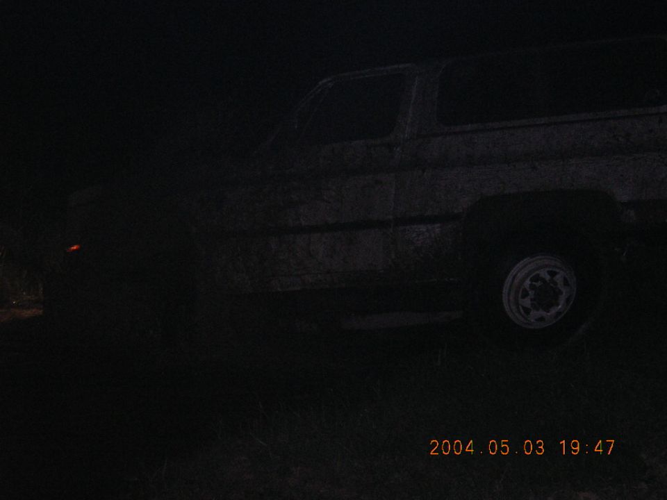 Dark night side view of a mud-caked square-body Chevrolet Blazer on chrome wheels