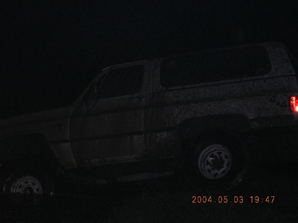 Night photo of a muddy square-body Chevrolet Blazer sitting in water, side view