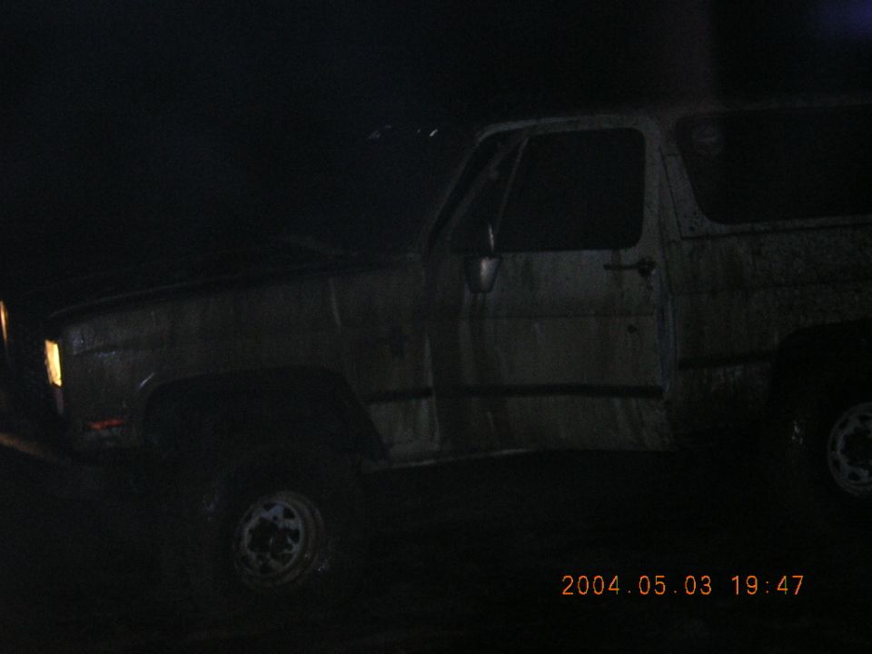 Night close-up of a mud-streaked square-body Chevrolet Blazer driver's side