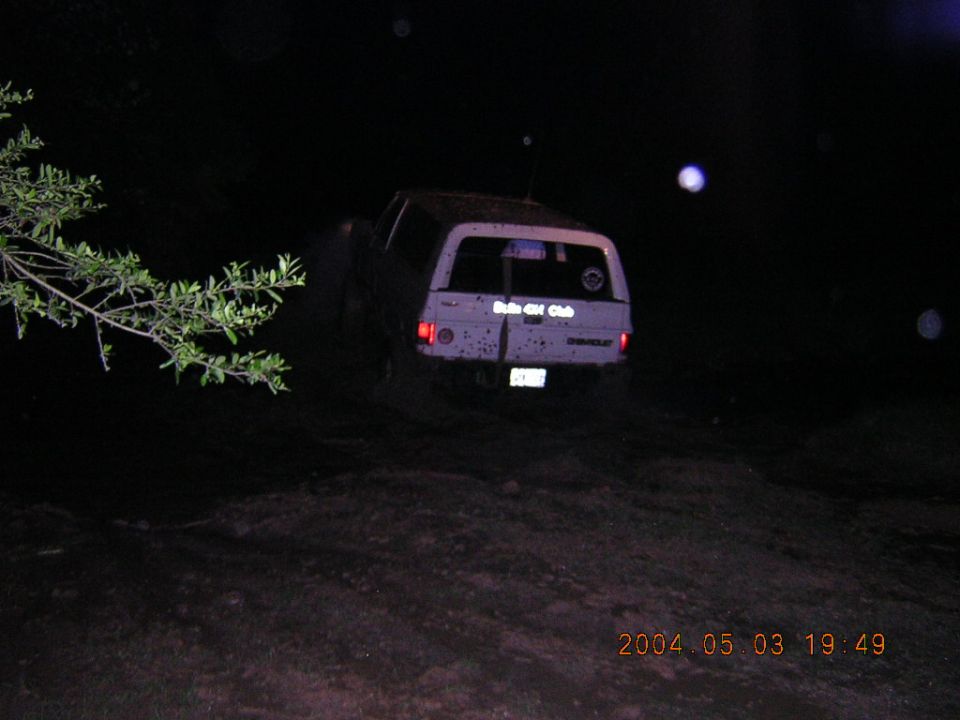 Night rear view of a mud-spattered white square-body Chevrolet Blazer with 4x4 club decal