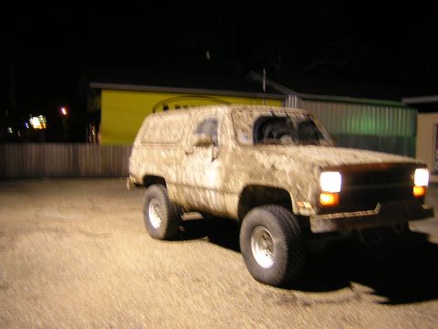 1984 Chevrolet Blazer - This heavily mud-caked SUV is parked outdoors at night, its headlights illuminating the ground.