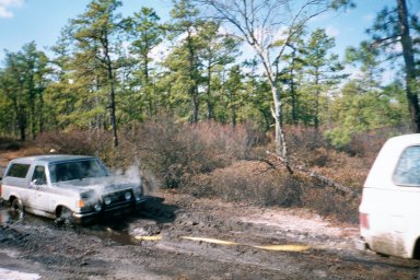 1979 Ford Bronco II - Ford Bronco stuck in muddy terrain with trees in the background.