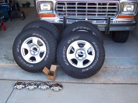 1979 Ford Bronco - Four Pathfinder SUV tires and wheels are displayed in front of a 1979 Ford Bronco's grille and bumper.