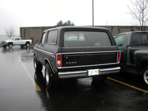 1979 Ford Bronco - Black 1978 Ford Bronco and a white pickup truck in a parking lot on a rainy day.