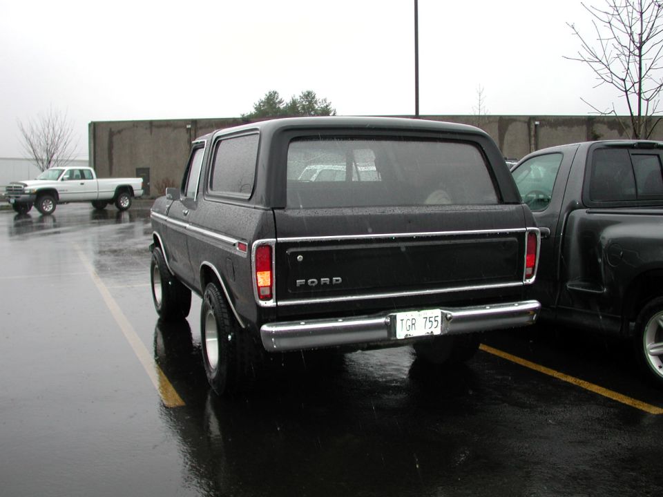 Black Ford Bronco SUV, rear view, parked on wet lot with FORD tailgate and TGR 755 plate.