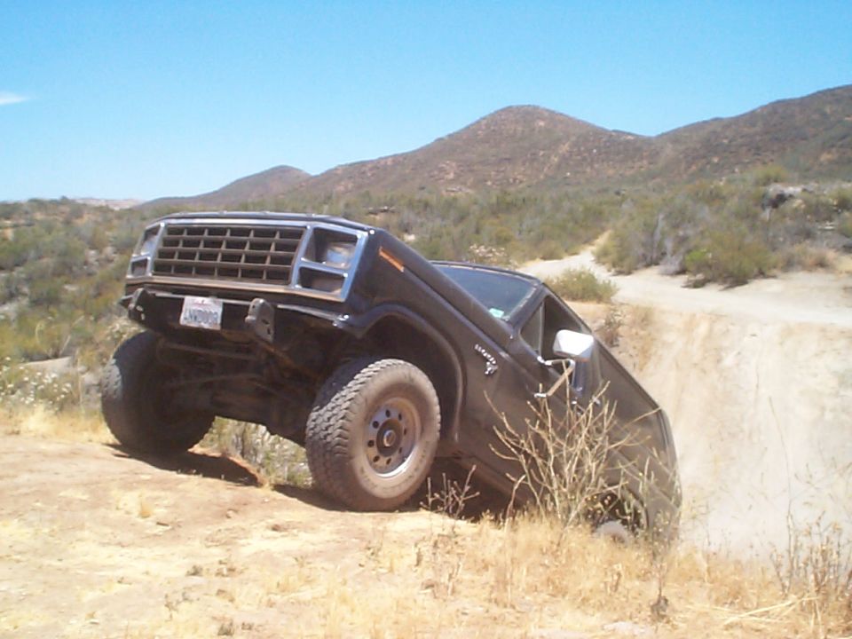 Black Ford Bronco tilted on a dirt hill, front grille visible