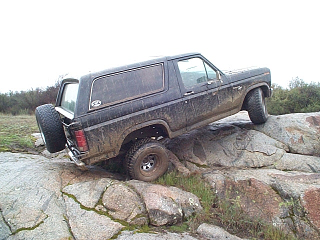 Black Ford Bronco climbing over large rocks on a trail