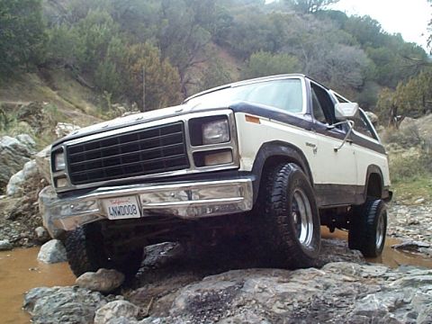 1981 Ford Bronco - This two-tone Ford Bronco is navigating a rocky, wet terrain.