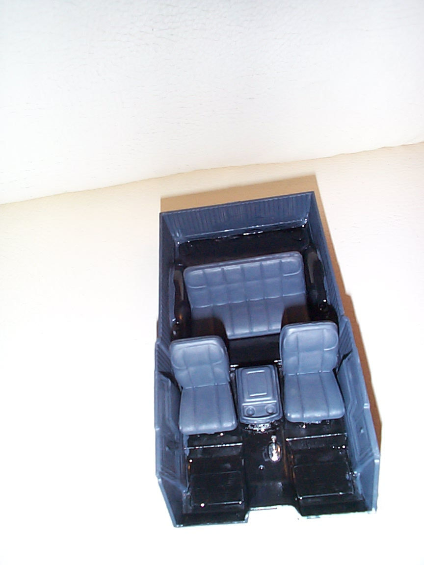 Overhead view of a scale model truck interior tub with gray bucket seats and center console
