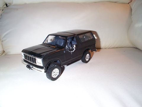 1981 Ford Bronco - Built scale model of a gloss-black early-'80s full-size Bronco posed on a white couch cushion, shown from the driver-side front three-quart…