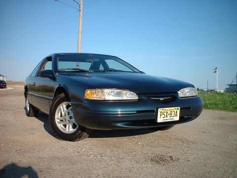 1996 Ford Thunderbird - A dark green 1996 Ford Thunderbird coupe is parked outdoors under a clear blue sky.