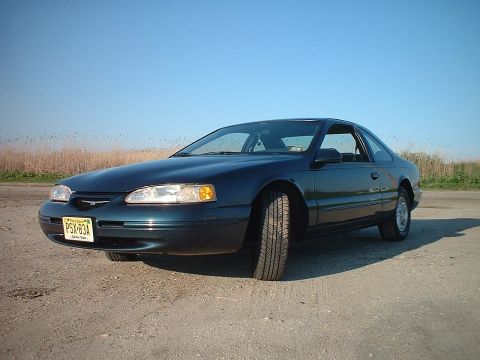 1996 Ford Thunderbird - 1996 Ford Thunderbird parked on a dirt road under a clear blue sky.