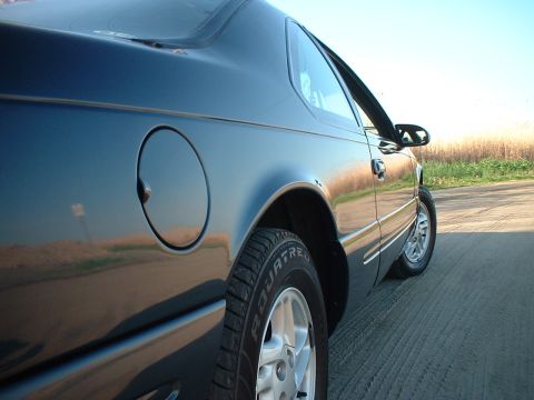1996 Ford Thunderbird - A dark blue coupe is viewed from the rear quarter, highlighting its side profile and wheel.