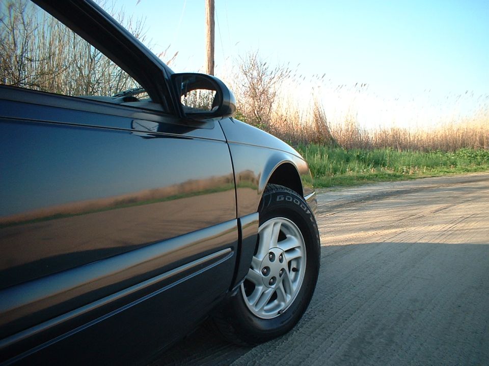 Dark blue car side view, showing wheel and side panel