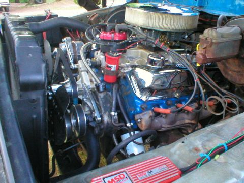 1978 Ford Bronco - Open engine bay of a blue truck showing a blue Ford V8 with chrome valve covers, MSD distributor and red plug wires, a chrome-topped open-e…