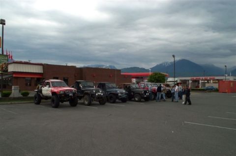 1992 Ford F-150 - A group of off-road vehicles are gathered in a parking lot under a cloudy sky.
