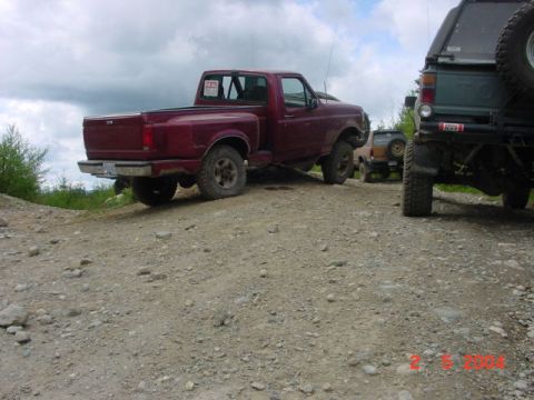 1992 Ford F-150 - A red 1992 Ford F-150 pickup truck is parked on a gravel road with other vehicles nearby.
