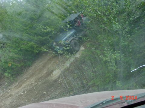 1992 Ford F-150 - A Jeep Wrangler navigates a challenging off-road incline amidst dense foliage.