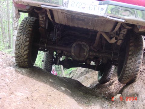1992 Ford F-150 - The rear axle and suspension of a truck are visible as it navigates a rocky, off-road path.