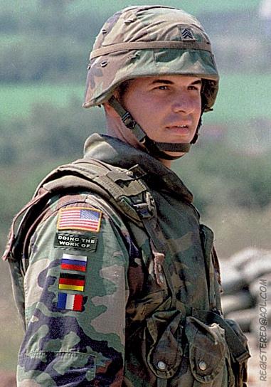 1997 Ford Expedition - A soldier wears a camouflage uniform adorned with an American flag patch and a patch reading "Doing the Work of" above several other nation…