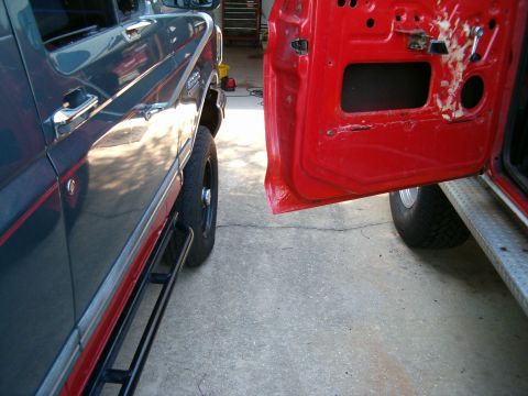 1979 Ford Bronco - A dark gray and red Ford Bronco is parked next to a vehicle with an open red door.
